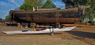 Seekajak neben altem Schiff